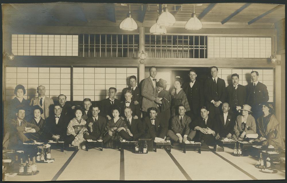  Black and white photograph of a group of men and women together in a tea house. 